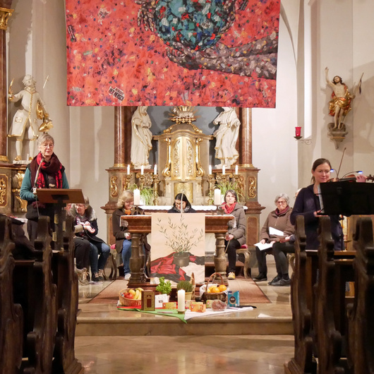 Im Gang in einer Kirche mit dem Blick auf dem Altarraum. In den Bänken sind mehrere Frauen.