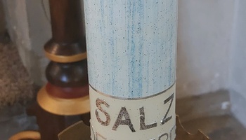 Eine weiße Kerze mit dem Text "Ihr seid das Salz der Erde" in Gold geschrieben.