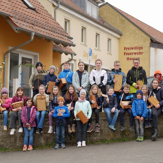 Ein schönes Gruppenbild vor einer Mauer. Kinder sitzen auf der Mauer oder stehen davor oder dahinter.