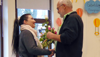 Ein Mann gratuliert der Jubilarin mit Blumen 