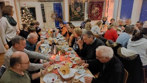 viele Menschen sitzen um einen reich gedeckten Frühstückstisch und essen und unterhalten sich