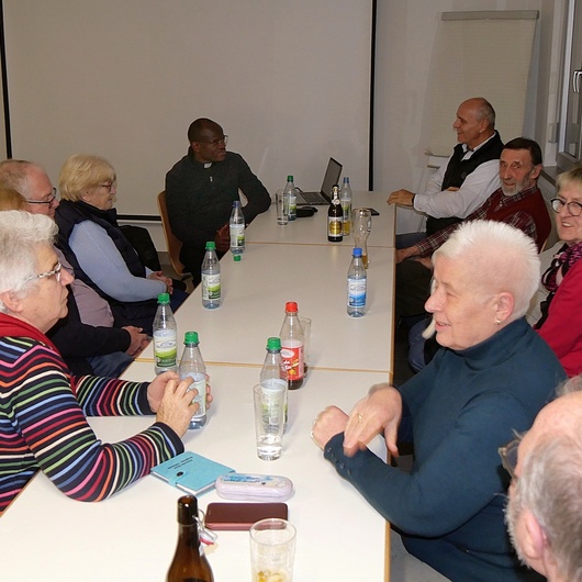 Eine kleine Gruppe sitzt um einen Tisch im Feuerwehrhaus von Gramschatz.