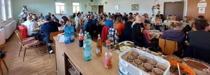 Ein großer Raum ist gefüllt mit vielen Menschen, die gemeinsam Essen. Im Vordergrund sind Muffins zu sehen.