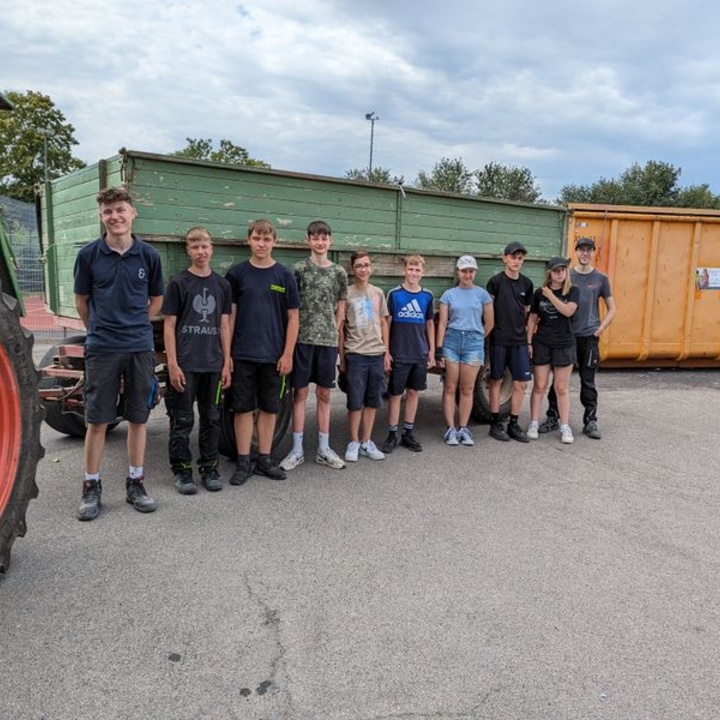 Gruppenbild der Altpapiersammler:innen neben einem Traktor und vor Containern