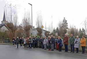 Eine Gruppe interessierter Menschen schaut der Segnung des Bildstocks zu.