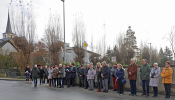 Eine Gruppe interessierter Menschen schaut der Segnung des Bildstocks zu.