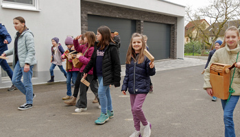 Eine kleine Gruppe an Kindern auf einer Dorfstraße. Sie rappeln und singen.