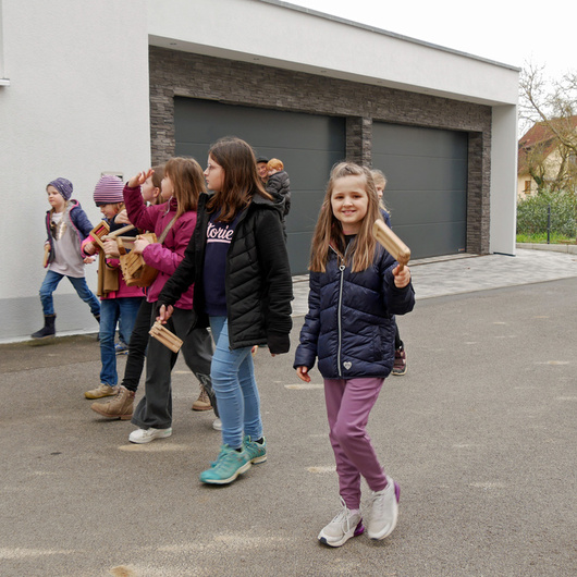 Eine kleine Gruppe an Kindern auf einer Dorfstraße. Sie rappeln und singen.