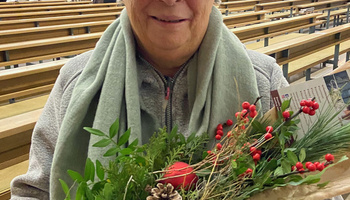 Lisbeth Rügemer blickt in die Kamera und hat einen Blumenstrauß in ihren Händen.