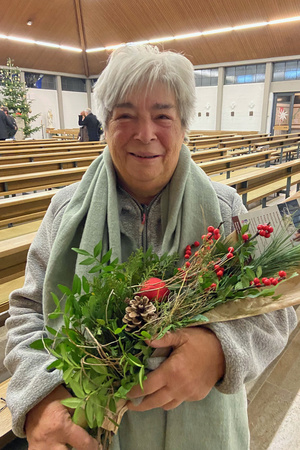 Lisbeth Rügemer blickt in die Kamera und hat einen Blumenstrauß in ihren Händen.