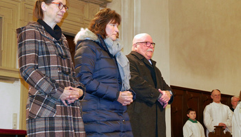 Drei Personen stehen im Altarraum und beten