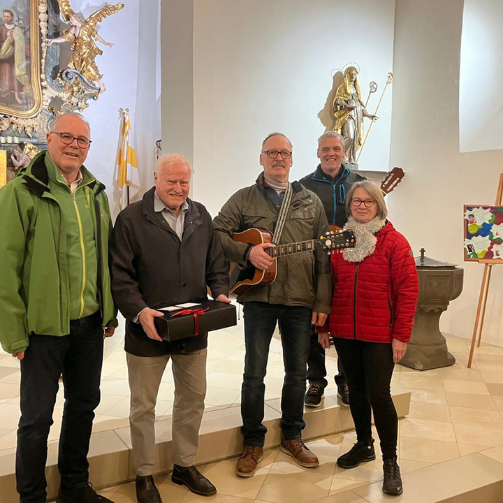 Vier Personen stehen im Altarraum der Riedener Kirche und lächeln in die Kamera.