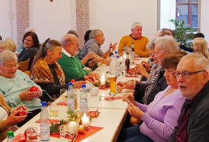 Senioren sitzen um einen Tisch und singen